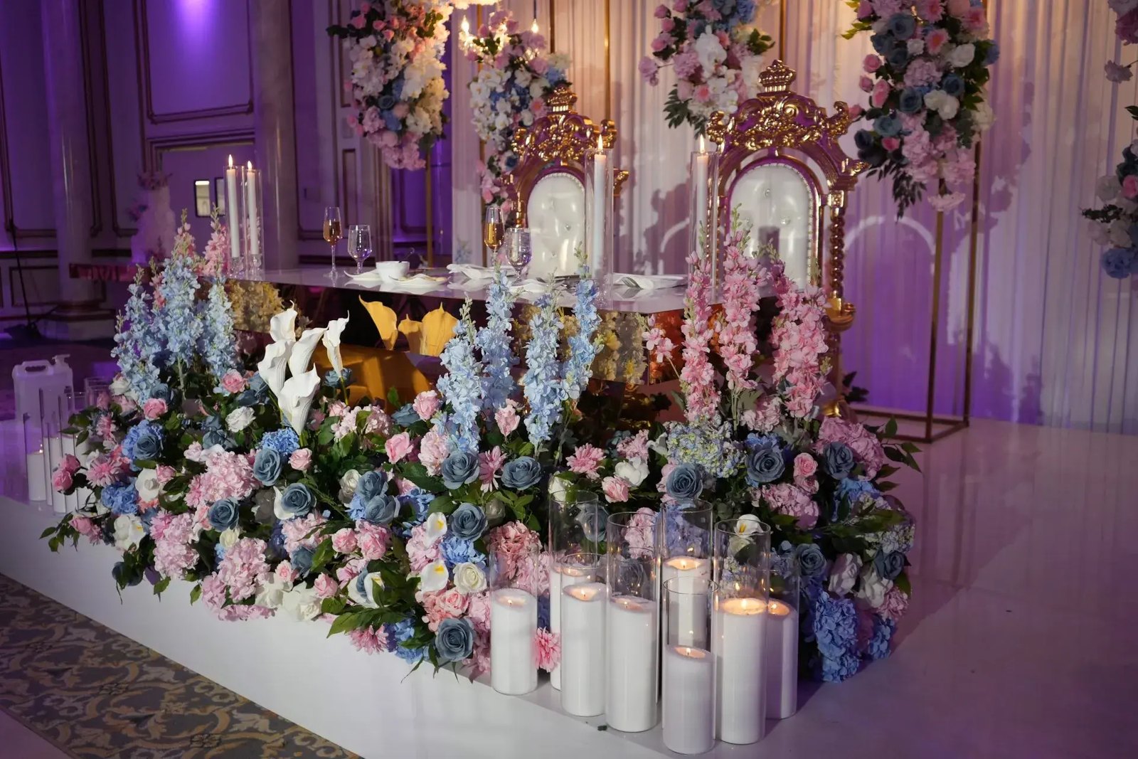 Let's Bloom Florist pink and blue floral sweetheart table with gold throne chairs and pillar candles at The Legacy Castle, NJ