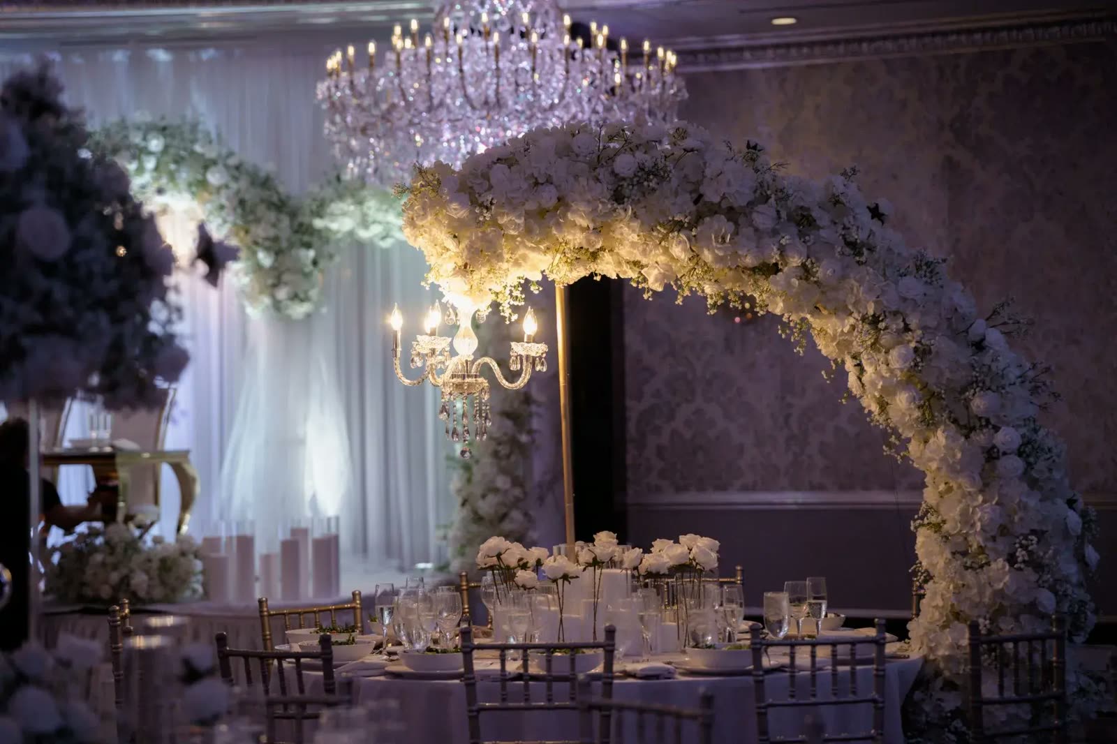 Let's Bloom Florist floral moon arch with white roses beside a crystal candelabra at The Venetian